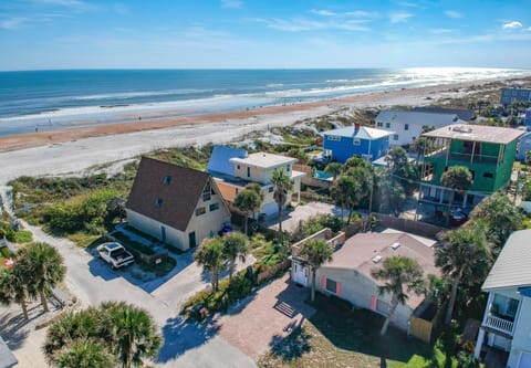 Aerial view of the beachside neighborhood with sandy dunes and ocean waves stretching along the coastline.
