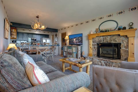 Sink into plush mountain-themed sofas before your stone fireplace, while the antler chandelier casts warm light across your open kitchen and dining area.