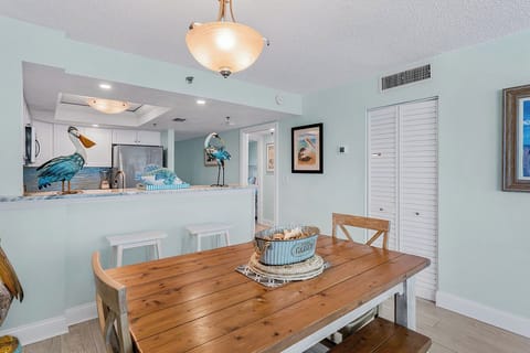 Your coastal dining space features a rustic wood table perfect for family meals, with charming pelican décor connecting to the nearby kitchen.