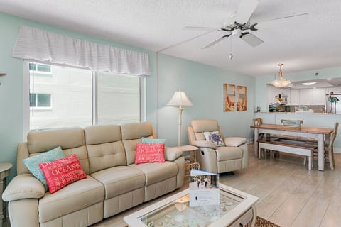 Relax in your bright, coastal-themed living space with comfy leather seating, ocean-inspired decor, and an open kitchen.