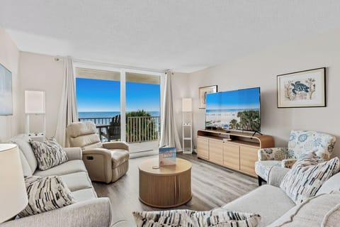 Relax in your coastal living room where ocean views stretch across the horizon through glass doors. Sink into plush seating as natural light fills the space and sea breezes invite you out to your private balcony.