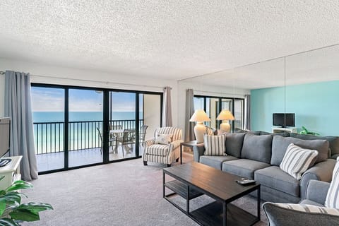Unwind in your spacious oceanfront living room with stunning sea views. The sectional sofa and striped chairs invite relaxation while the balcony beckons.