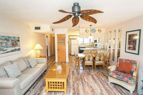 - Spacious open layout featuring sofa, dining table, and decor with coastal flair
- Ceiling fan and wood flooring add both comfort and style to the room
- Bright and airy space ideal for gatherings, meals, or evening relaxation