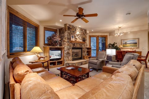 Sink into plush leather seating by your stone fireplace, where warm lighting and mountain views create the perfect evening retreat.