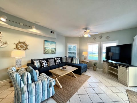 Unwind in your coastal-themed living room with plush sectional seating, nautical decor, and large TV for cozy evenings by the sea.