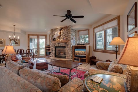 Unwind in this cozy living room where rustic stone fireplace warmth meets comfortable seating for perfect mountain evenings together.