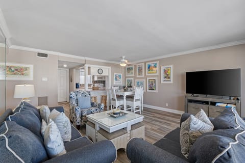 Relax in your spacious living room with plush seating, coastal art, and entertainment center perfect for family gatherings.