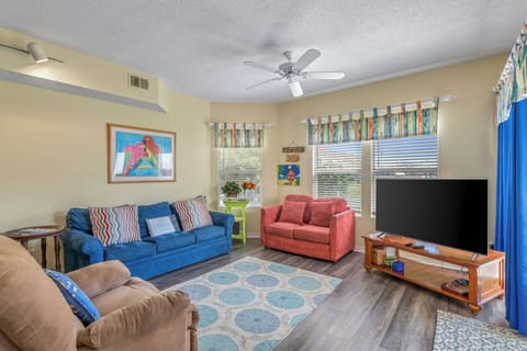 Relax in your spacious living area with plush seating, vibrant coastal décor, and large screen TV for cozy movie nights.
