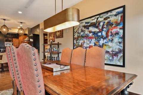 Gather around your elegant dining table beneath warm pendant lighting, with vibrant artwork creating the perfect atmosphere for memorable meals.