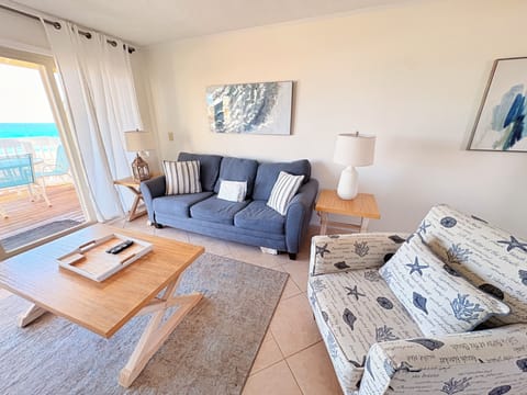 Relax in your bright, coastal-themed living room with comfortable seating and stunning sea views from your private balcony.