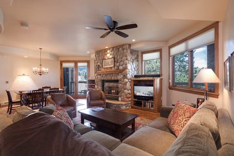 Sink into plush sofas by your stone fireplace, where mountain views through picture windows create the perfect backdrop for cozy evenings together.
