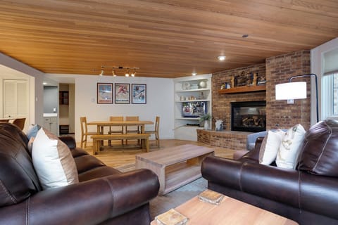 Unwind in your spacious living room where warm wood ceilings meet cozy leather seating around a crackling brick fireplace.