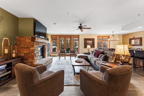 Unwind in your spacious living room where rustic charm meets modern comfort, complete with a stone fireplace and mountain views.