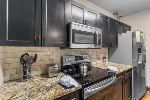 Full kitchen with granite countertops, stainless steel appliances, and breakfast bar seating.