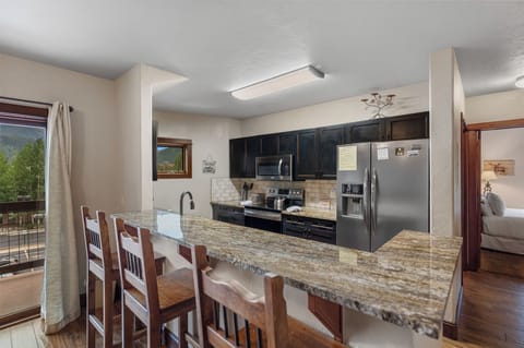 Full kitchen with granite countertops, stainless steel appliances, and breakfast bar seating.