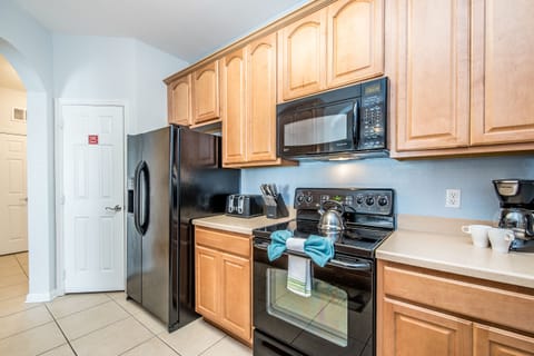 Discover a fully furnished kitchen equipped with a spacious refrigerator, providing ample storage for all your culinary delights and refreshments.