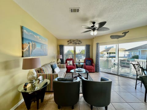 Unwind in your bright, coastal-themed living space with comfy seating and balcony doors opening to peaceful neighborhood views.