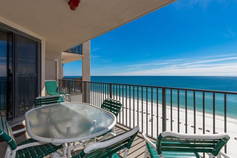 Relax at the round table with green chairs, enjoying views of the calm water and beach from your spacious balcony