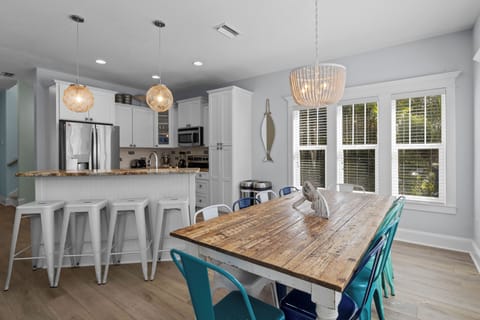 Gather around this gorgeous open kitchen and dining space with rustic charm, modern touches, and abundant natural light streaming through large windows.
