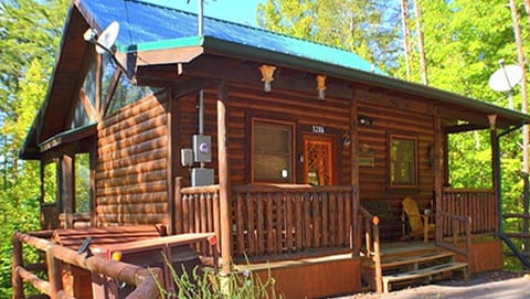 Charming log cabin exterior with a welcoming front porch nestled in the trees at Always Kiss Me Goodnight in Pigeon Forge, Tennessee — just 10 minutes from downtown Pigeon Forge
