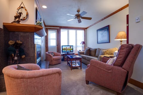 Unwind in your cozy living room with plush seating, warm fireplace, and mountain views through large windows.