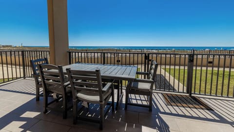 Enjoy meals or morning coffee at the outdoor dining table with a view of the sparkling beach in the distance