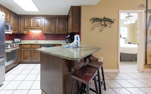 Prepare meals in the inviting kitchen with rich wood cabinetry, a spacious countertop, and stylish breakfast bar
