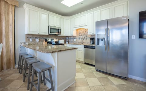 Modern kitchen featuring granite countertops, a breakfast bar, and seating at the breakfast bar with stylish gray stools