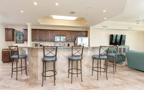 The kitchen features wood cabinetry, granite countertops, and a breakfast bar with stylish seating, perfect for casual dining