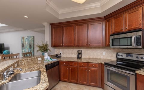 The kitchen features rich wood cabinetry, stainless appliances, and a convenient coffee maker for a delightful experience