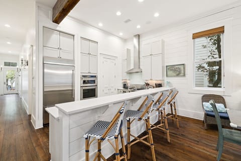 Gather around this stunning kitchen island where crisp white cabinets and warm wood beams create your perfect culinary haven.