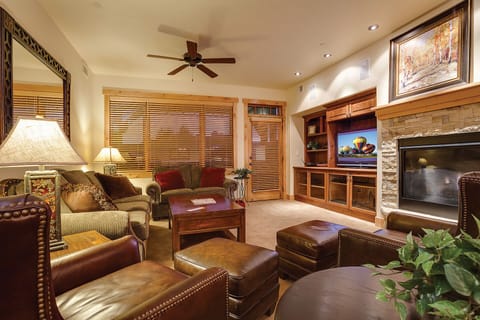 Sink into plush leather seating by your stone fireplace, where rich wood tones and warm lighting create the perfect evening retreat.