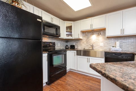 Cook and gather in this kitchen featuring sleek black appliances and stylish granite countertops and backsplash
