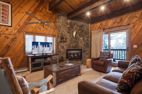 Cozy up by the crackling stone fireplace in your mountain retreat, where rustic wood beams and leather seating create the perfect après-ski atmosphere.
