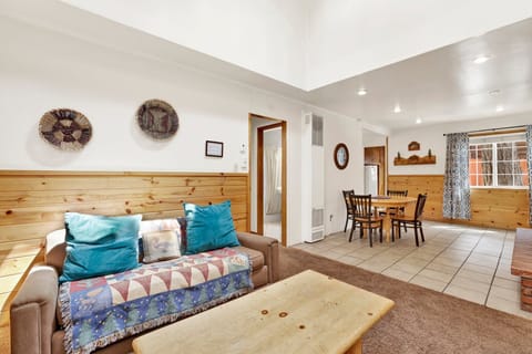 Cozy mountain living room with a stone fireplace, comfy seating, and smart TV—perfect for relaxing evenings, movie nights, and warm cabin vibes after outdoor adventures.