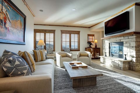 Sink into plush seating by the fireplace, where mountain views frame your mornings and entertainment awaits on the flat-screen TV—your perfect retreat for relaxing together.