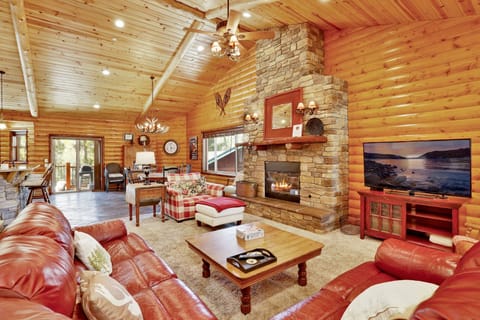Cozy mountain living room with wood ceilings, stone fireplace, comfy seating, and smart TV—perfect for relaxing evenings, movie nights, and warm cabin vibes after outdoor adventures.