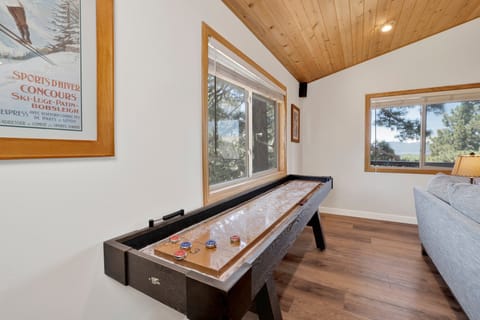 This dedicated gaming spot features a full-sized shuffleboard table set against large windows with scenic vistas.