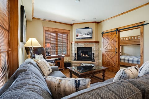 Cozy up by the stone fireplace while the kids enjoy bunk beds behind rustic sliding doors.