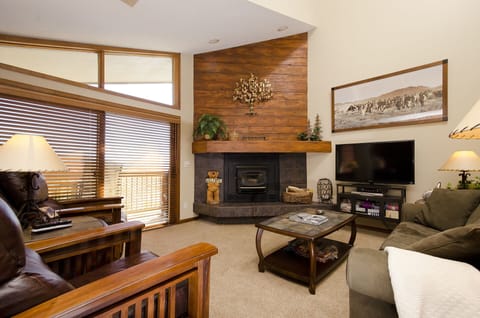 Unwind in your inviting living space featuring rich wood accents, a cozy fireplace, and modern entertainment center for perfect mountain evenings.