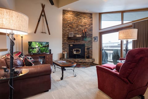 Cozy up by your stone fireplace in this inviting living space with plush seating and mountain views from your private balcony.