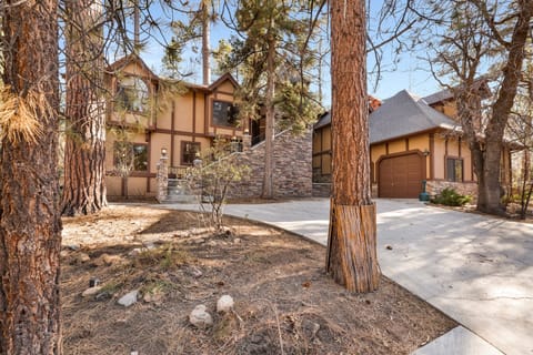 A stunning multi-level cabin nestled among mature pines. The exterior features classic timber framing and stone accents, with a spacious driveway leading to a private garage—perfect for a secluded nature getaway.