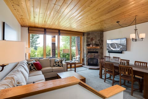 Cozy mountain retreat with stone fireplace, plush seating, and panoramic windows framing alpine views for your perfect getaway.