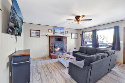 Cozy cabin living room with a stone fireplace, comfy seating, with an amazing view of the lake—perfect for relaxing evenings, movie nights, and unforgettable mountain getaways.