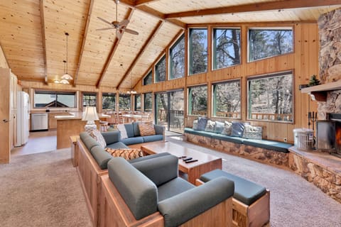 Stunning open-concept cabin with soaring wood ceilings, panoramic forest views, cozy fireplace, and spacious living area—perfect for group gatherings, relaxing escapes, and unforgettable mountain stays.