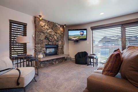 Unwind in this cozy living space featuring a stunning stone fireplace and wall-mounted TV for your entertainment.