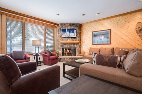 Cozy up by your stone fireplace with plush seating and warm wood accents creating the perfect mountain retreat atmosphere.