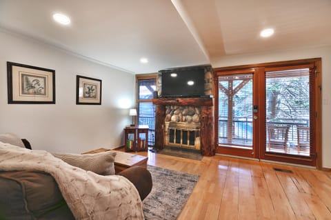 Open living area with hardwood floors, gas fireplace and mantle mounted TV