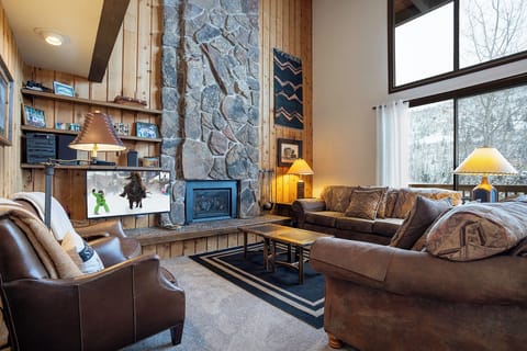 Sink into plush leather seating beside the stone fireplace, where warm lamps create perfect ambiance for your mountain getaway evenings.