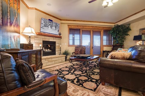 Sink into plush leather seating by your crackling fireplace, where warm wood tones and mountain views create your perfect retreat.
